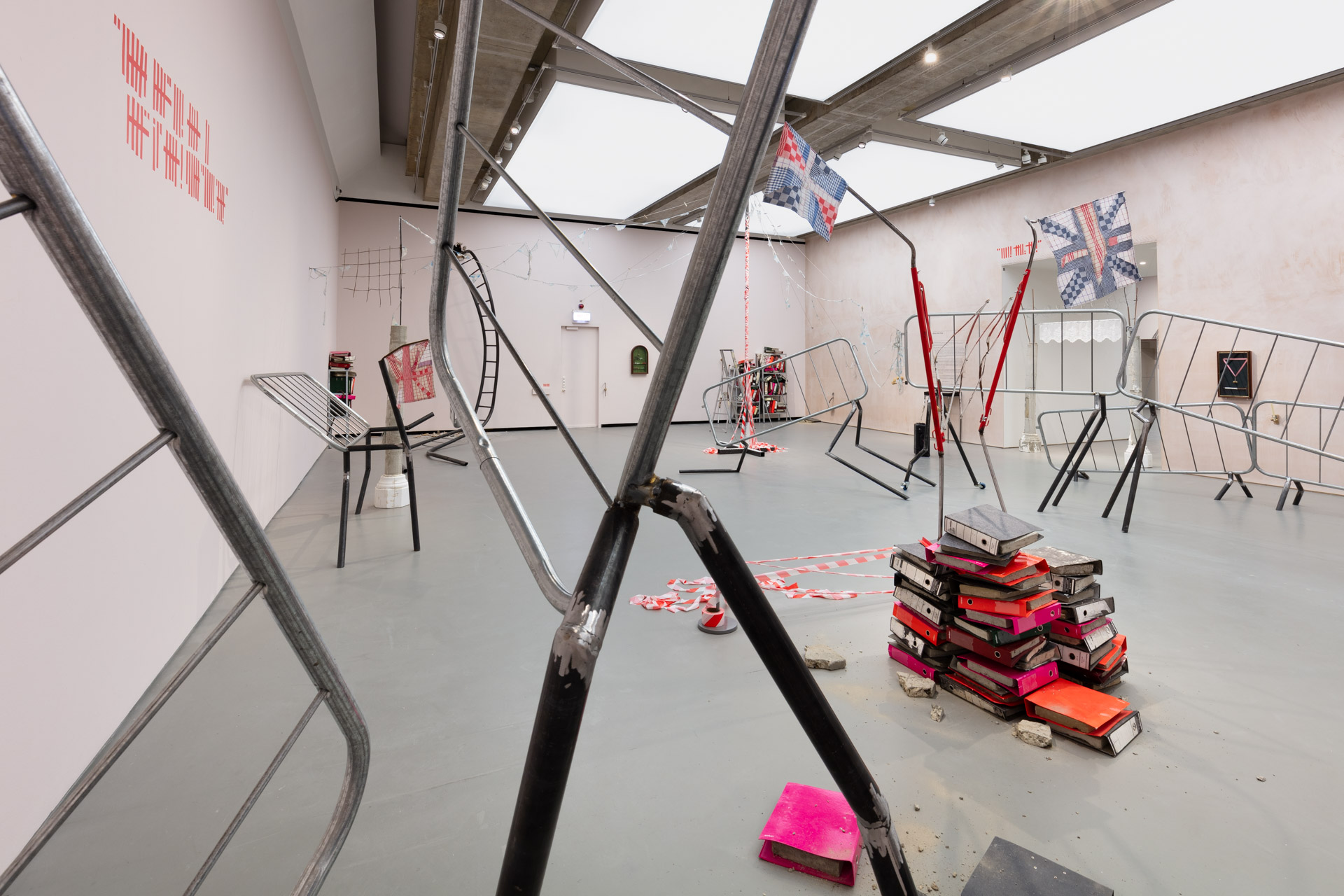 Sculptures across the gallery made from crowd control railings, police tape, patchwork union flags, discarded ring binders and other scrap metal